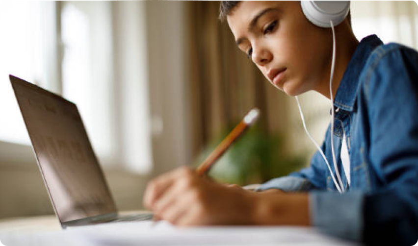a photo of a boy wearing headphones and using a laptop
